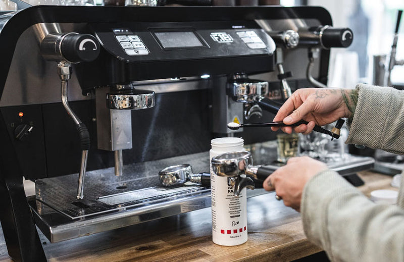 Person cleaning an espresso machin